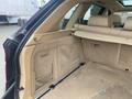 Interior view of the trunk area of a 2009 BMW X5 showing beige upholstery and storage compartments