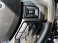 Close-up of the steering wheel controls in a 2021 Ford F-550 featuring buttons for volume track navigation and phone connectivity