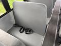 A gray bus seat with a black seatbelt lying loosely across it