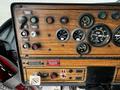Dashboard of a 1991 Sutphen Deluge featuring analog gauges switches and control buttons in a wooden panel design with a sticker and a keychain attached