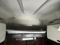 Interior of a 2022 Freightliner Cascadia with a sleeping area featuring a mattress and storage space above the cab
