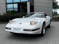A white 1992 Chevrolet Corvette with pop-up headlights parked in front of a building