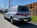 A silver 2013 Lincoln MKT hearse with a sleek design featuring a prominent raised section at the back and decorative chrome accents