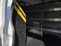 A 2019 GMC Savana van with an interior featuring a tall, black tool rack with yellow stripes and metal shelving units against the back wall