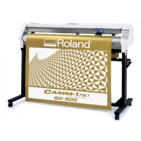A Roland CAMM-1 GX-500 vinyl cutter with a large gold sheet displaying a geometric pattern currently being cut by the machine