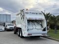 A 2010 Autocar Xpeditor garbage truck with a white body and rear loading mechanism featuring lights and a compacting compartment