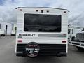A 2022 Keystone Hideout RDWE 20RDWE travel trailer featuring a white and black exterior and a rear window with a round travel-themed spare tire cover