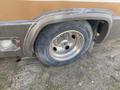 A close-up view of a flat tire on a 1987 Chevrolet Fleetwood Pace Arrow showing a silver wheel and worn tire tread