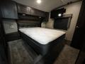 A spacious bedroom in a 2021 Grand Design Recreational 311BHS featuring a large bed with a mattress and a wall-mounted TV above it