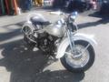 A vintage 1947 Harley-Davidson WL motorcycle with a silver body and white fenders, featuring a classic design and a prominent Harley-Davidson logo on the fuel tank