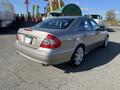 A 2007 Mercedes-Benz E-Class parked with a silver exterior and distinctive rear design featuring dual exhaust outlets and alloy wheels