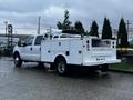 A white 2014 Ford F-350 SD truck with dual rear wheels and a utility body featuring multiple compartments and equipment mounts on the bed