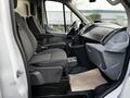 Interior of a 2017 Ford Transit with two gray seats and a dashboard featuring controls and storage compartments