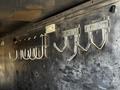 A set of metal hooks mounted on a silver metallic surface designed for storage or hanging items in a vehicle