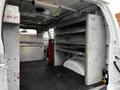 Interior of a 2011 Ford Econoline van featuring metal shelving units and a first aid kit mounted on the wall