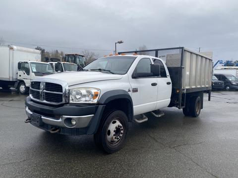 A 2008 Dodge Ram 5500 pickup truck with a flatbed and mesh sides parked on a lot