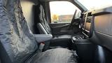 Interior of a 2005 Chevrolet Express showing two front seats covered with black seat covers and a center console with cup holders