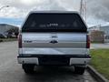 A silver 2014 Ford F-150 truck viewed from the rear with a black tonneau cover and the Ford logo visible on the tailgate