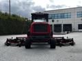 A red 2012 Toro Groundsmaster mower with a cab and multiple cutting decks is positioned facing forward with large rear wheels visible