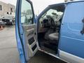 A blue 2009 Ford Econoline van with the driver's side door open showing the interior and driver's seat