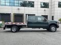 A green 2008 Ford F-550 flatbed truck with a dual cab configuration and a silver flatbed attachment on the back