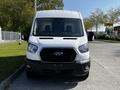 A white 2022 Ford Transit van viewed from the front featuring a black grille and large headlights with a spacious windshield and two front seats visible inside