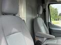 Two grey seats of a 2017 Ford Transit with adjustable headrests and armrests positioned inside the vehicle cabin