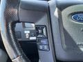 Close-up of the steering wheel controls for a 2014 Ford F-150 highlighting buttons for navigation and cruise control settings