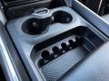 A close-up of the center console of a 2022 RAM 3500 featuring two cup holders and storage compartments for small items and beverages