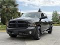 A black 2018 RAM 1500 truck with a bold grille and large tires parked in a driveway