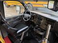Interior view of a 2019 Chevrolet Express with a driver's seat and dashboard featuring various controls and cup holders