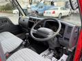 Interior of a 2001 Toyota Dyna featuring a gray dashboard with gauges a steering wheel and a textured seat with a gear stick in the center console