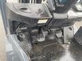 Close-up of the control panel and foot pedals of a 2011 Toyota 028FG15 forklift showing the operator's controls and floor area with some moisture visible
