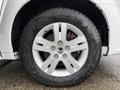 A 2017 Dodge Grand Caravan wheel featuring a silver alloy rim and a black tire with visible tread and water droplets on the surface