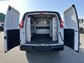 A 2014 Chevrolet Express cargo van with its rear doors open showcasing an empty interior with storage shelves along the sides