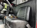 A black leather seat in a firetruck with a textured surface and a seatbelt beside a wooden console
