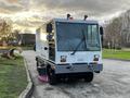 A gray and white 2007 Tennant Sentinel vacuum cleaner with large wheels and a front-facing cab designed for street cleaning