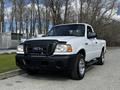 A white 2010 Ford Ranger pickup truck with a black grille and front bumper parked on a concrete surface
