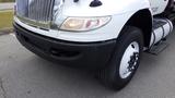 A white 2015 International DuraStar 4300 truck with a prominent grill and round headlights situated in the foreground with a large black tire