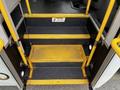 Interior steps of a 2016 Ford Econoline featuring yellow handrails and a caution sign on the floor with non-slip textured surface