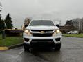 A 2018 Chevrolet Colorado driving towards the camera with its headlights on and front grille prominently displayed