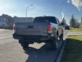 A 2021 Toyota Tacoma in gray parked on the street with its tailgate visible and the rear view showcasing its design and branding