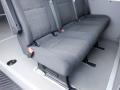 Three gray upholstered seats arranged in a row inside a vehicle with seatbelts attached