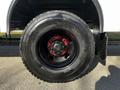 A close-up of a black wheel with a red rim and lug nuts mounted on a 2022 Blue Bird Vision vehicle