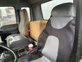 A 2006 GMC F7B042 truck interior featuring two seats one covered and one with visible wear with a central console and a coffee cup on it