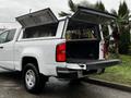 A white 2018 Chevrolet Colorado with its rear doors open revealing a spacious truck bed and cargo area