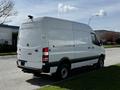 A 2017 Mercedes-Benz Sprinter van with a white exterior parked on a street showing its rear and side profile