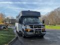 A 2018 Chevrolet Express bus with a white body and black front is parked with a front-mounted grill guard attached