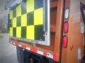 A 2016 International WorkStar 7500 truck with a brightly colored checkered pattern on a safety sign attached to the back stating its visibility precautions
