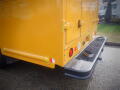 A yellow 2008 Freightliner MT45 Chassis with a textured metal step and various lights installed on the rear panel